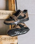 Twee Jordan Jumpman Jack TR schoenen. Een paar hangt, de andere ligt met witte lijnen op de zwarte zool.