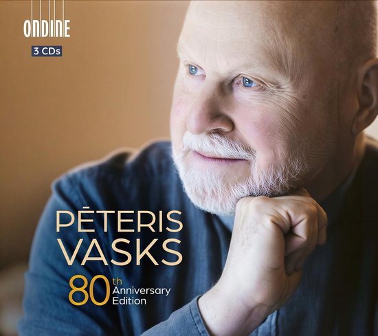 Close-up portret van componist Pēteris Vasks, met blauwe ogen en grijze baard. 'Pēteris Vasks 80th Anniversary Edition 3 CDs' in gouden letters.