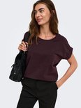 Model draagt donkerpaarse top met korte mouwen en glitterdetails, met een zwarte tas.