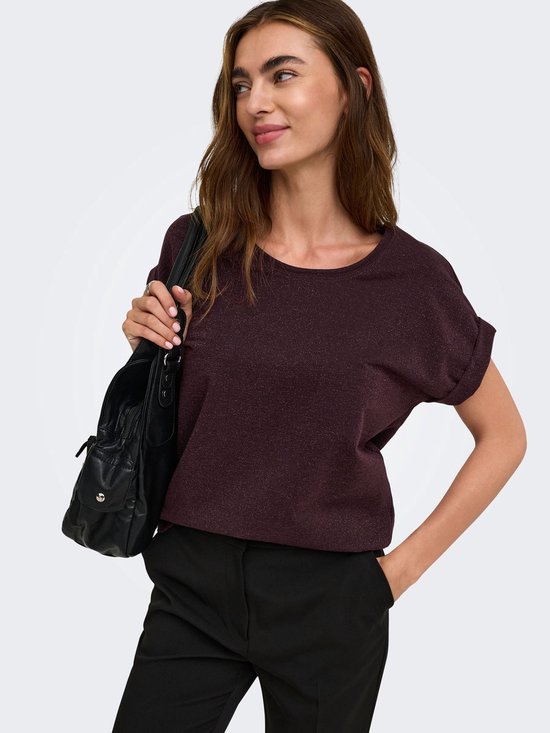 Model draagt donkerpaarse top met korte mouwen en glitterdetails, met een zwarte tas.