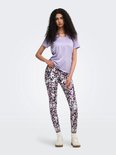 Model in paars sportshirt met V-hals en een veelkleurige legging met abstracte print. Ze houdt haar shirt op.