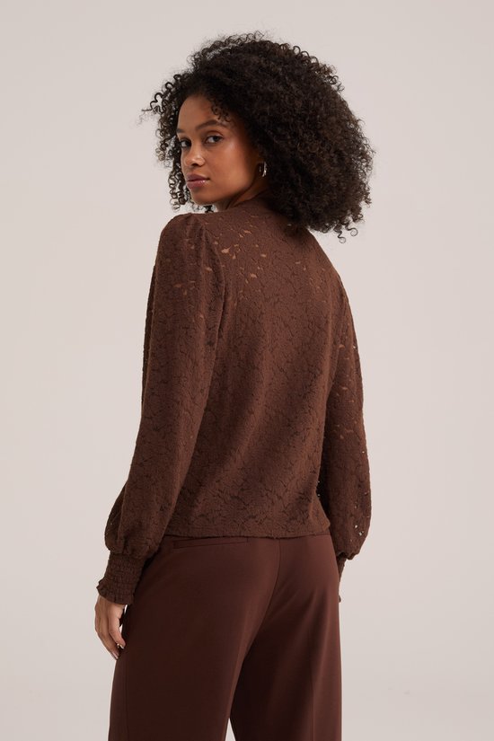 Model van achteren gezien in bruine kanten top met pofmouwen en bruine broek.