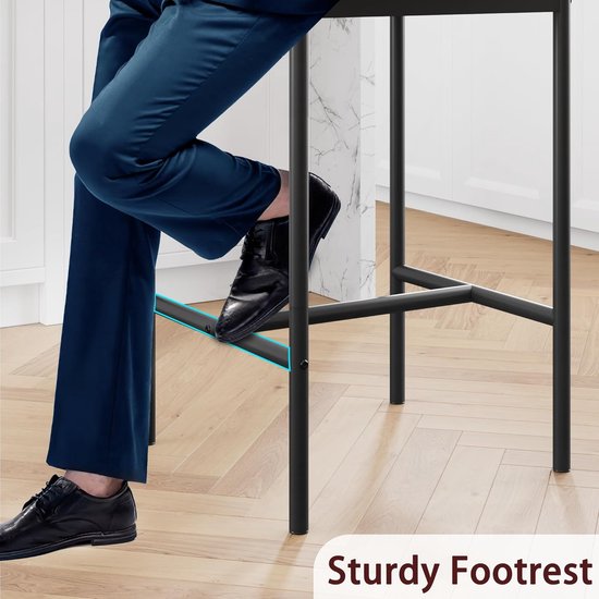 Detailopname van het metalen onderstel van een zwarte barkruk, met tekst 'Sturdy Footrest'.