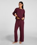 Dames, een donkerrode pyjamaset met lange mouwen en broek, model laat de pyjamabroek zien.