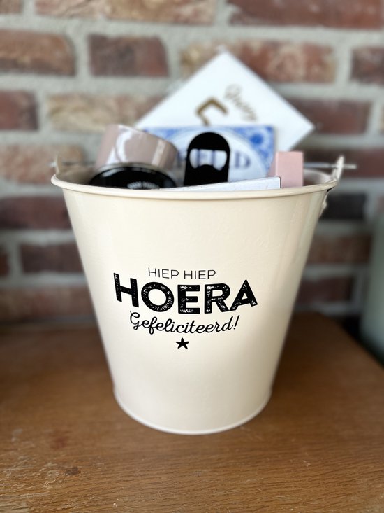 Crème zinken emmer met de tekst 'HIỆP HIỆP HOERA Gefeliciteerd!' met diverse cadeautjes erin.