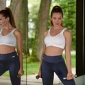 Model met witte sport-prothesebeha met rits en donkerblauwe sportbroek, houdt halters vast.