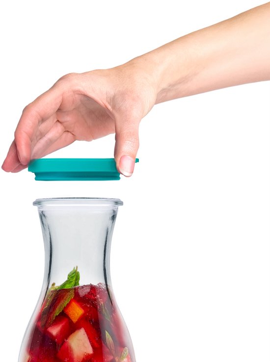 Glazen karaf gevuld met fruit, met een turquoise deksel in een hand.