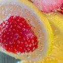 Close-up van aardbeien en citroenschijfjes in bruisend water met bubbels.