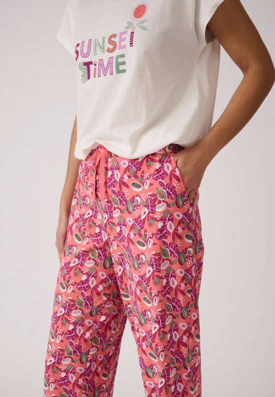 Dames in een witte top met 'SUNSET TIME' opdruk en een roze pyjamabroek met tropische print.