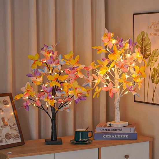 Twee decoratieve bomen met vlinders en led-lampjes op een dressoir.