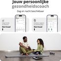 Un homme et une jeune fille sont assis sur des tapis de yoga. L'homme regarde son téléphone, la jeune fille le regarde. Derrière eux, deux iPhones affichant des données de santé.
