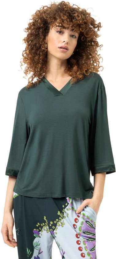 Model met krullend haar draagt een donkergroen T-shirt met 3/4 mouwen en satijnen boorden.