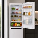 Open witte Heinner koel-vriescombinatie gevuld met diverse etenswaren, waaronder groenten en fruit.