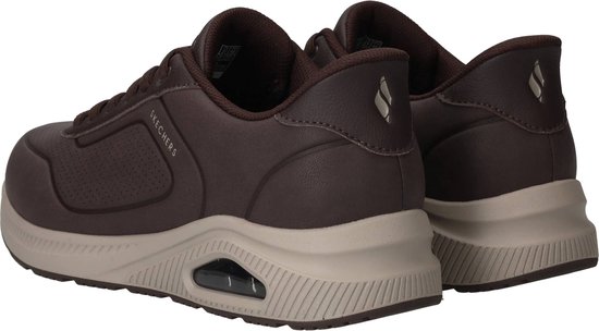 Donkerbruine Skechers sneakers met beige zool en een zichtbare demping in de hiel.