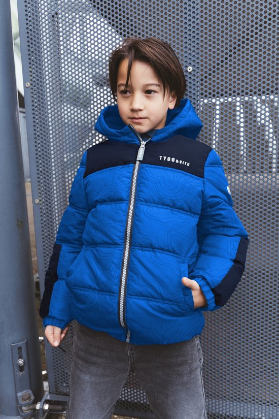 Jongen in een blauw met zwart gewatteerd jack met contourpatroon en capuchon. TYGO & VITO logo op borst.