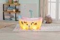 Roze babybadje met bubbels, verlichting en een onderwaterprint, in een badkamer.