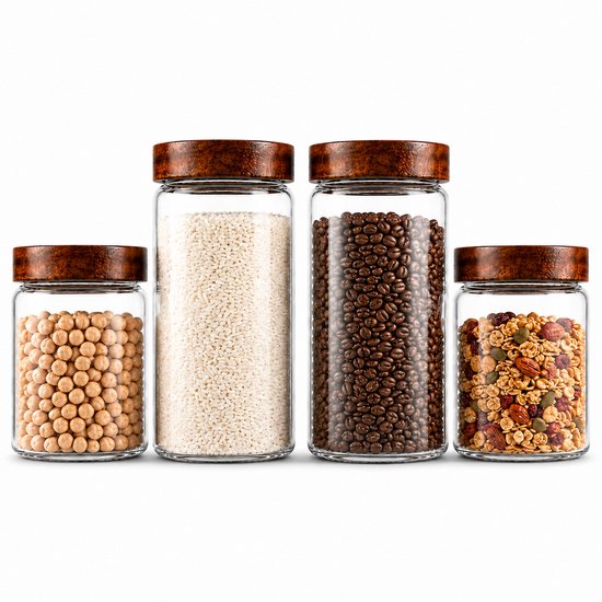 Vier glazen voorraadpotten met houten deksels, gevuld met kikkererwten, rijst, koffiebonen en ontbijtgranen.