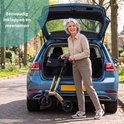 Vrolijke vrouw met rollator bij een open kofferbak