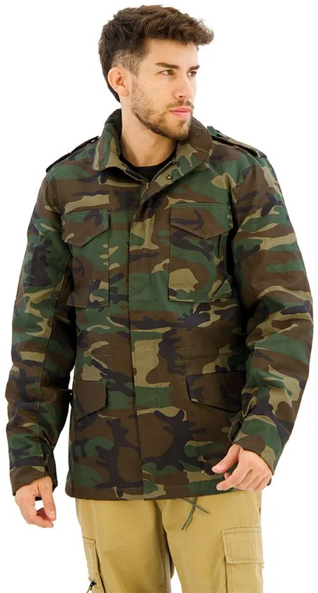 Man met een groene camouflage jas en kaki broek, kijkt weg van de camera. De jas heeft vier zakken aan de voorkant.
