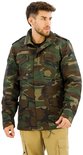 Man met een groene camouflage jas en kaki broek, kijkt weg van de camera. De jas heeft vier zakken aan de voorkant.