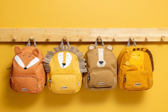 Vier kinderrugzakken hangend aan een houten rek: vos, leeuw, beer en giraffe. Allen met dierenprint en stippenpatroon.