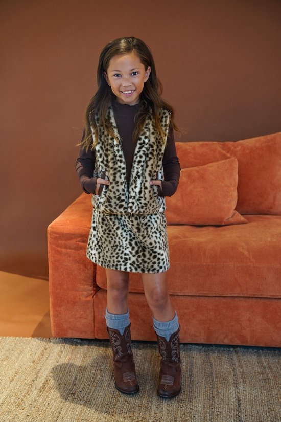 Meisje in luipaardprint bodywarmer, bruine coltrui, minirok en grijze sokken met laarzen.