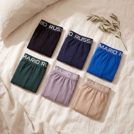 Zes Mario Russo boxershorts uitgestald op een bed. Kleuren: zwart, donkerblauw, blauw, groen, paars en beige.