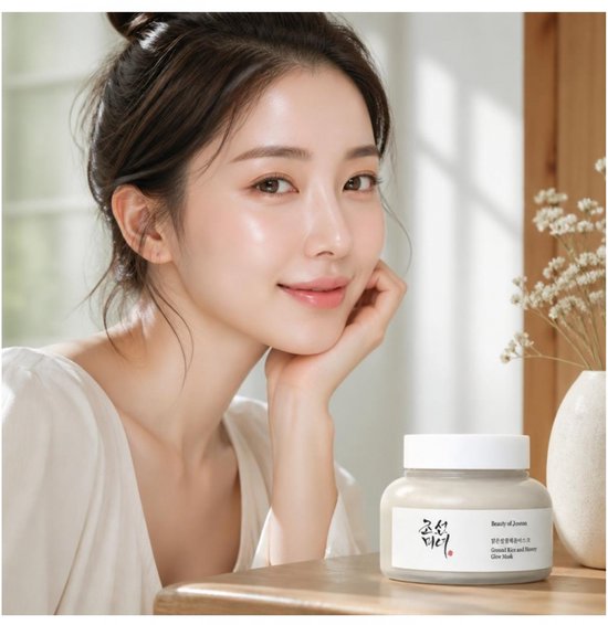Vrouw met stralende huid houdt potje Ground Rice and Honey Glow Mask van Beauty of Joseon vast.