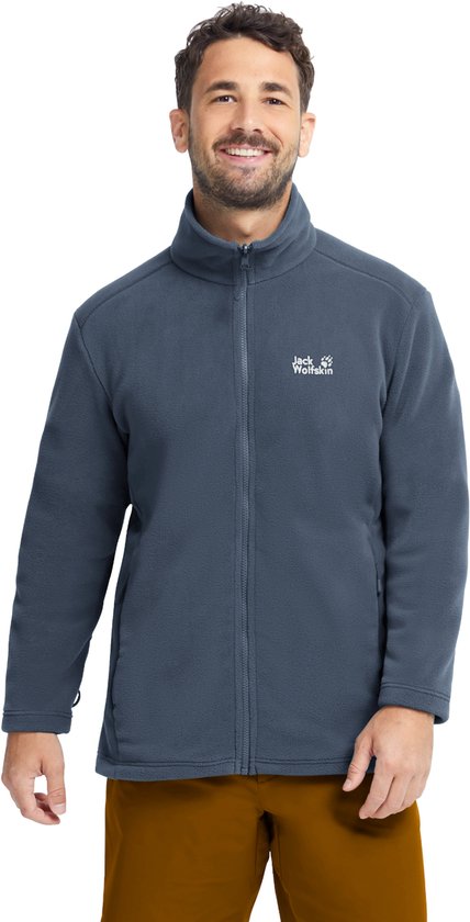 Un homme souriant porte une veste polaire bleue Jack Wolfskin zippée avec un pantalon marron.