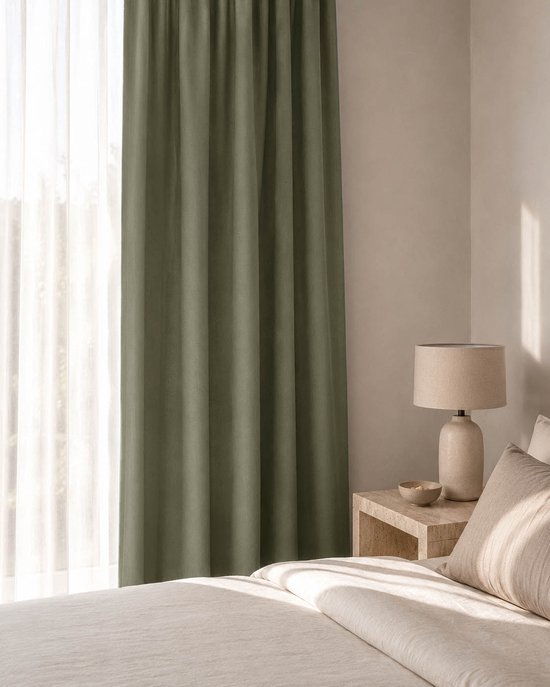 Slaapkamer met een bed en een raam met beige en olijfgroene gordijnen, lamp op nachtkastje.
