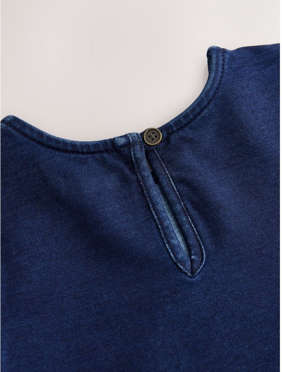 Close-up van de donkerblauwe denim jurk met een knoopsluiting aan de achterkant.