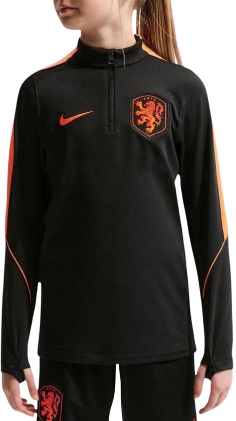 Meisje met paardenstaart in zwart Nike trainingsjack met oranje accenten, logo en KNVB-wapen.