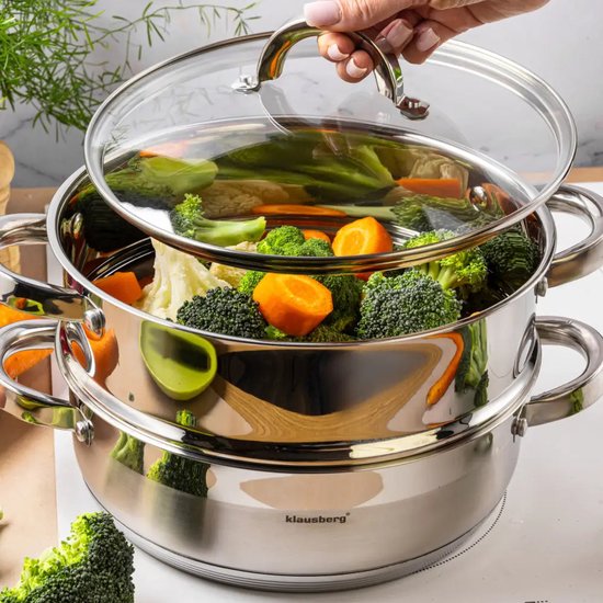 RVS stoompan met glazen deksel, gevuld met broccoli, bloemkool en wortel. Een hand tilt het deksel op.