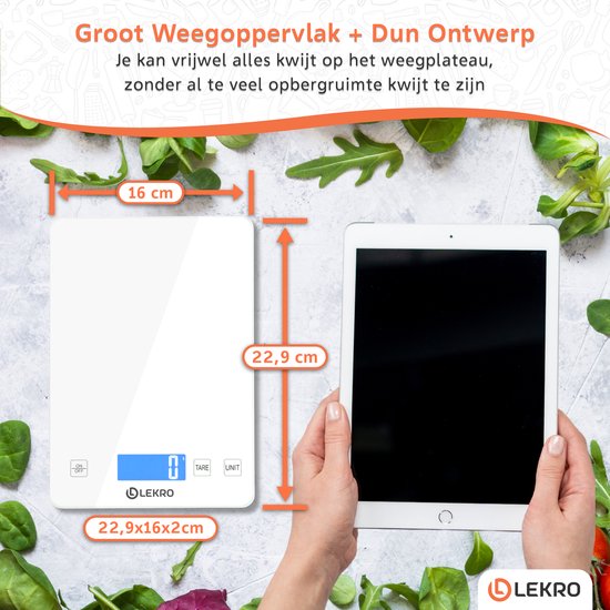 Vergelijking van de afmetingen van de witte digitale keukenweegschaal (16x22,9x2cm) met een tablet. Omringd door verse groenten.