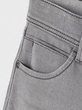 Grijze jeans met een kleine zak en een metalen knoop.