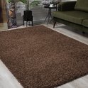 Bruin shaggy vloerkleed in een woonkamer met een groene bank.