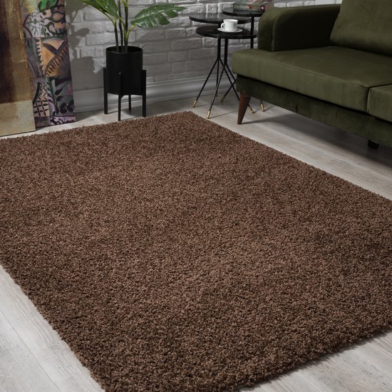 Bruin shaggy vloerkleed in een woonkamer met een groene bank.