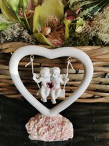 schommel in hartvorm met 2 engeltjes-scherubijntjes met roze hart op voetstuk roze roosjes