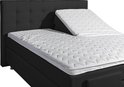 Zwart boxspringbed met verstelbaar hoofdeinde en wit, ruitvormig gestikt matras.