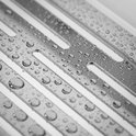 Image détaillée de gouttelettes d'eau sur les nervures d'une étagère de douche chromée.