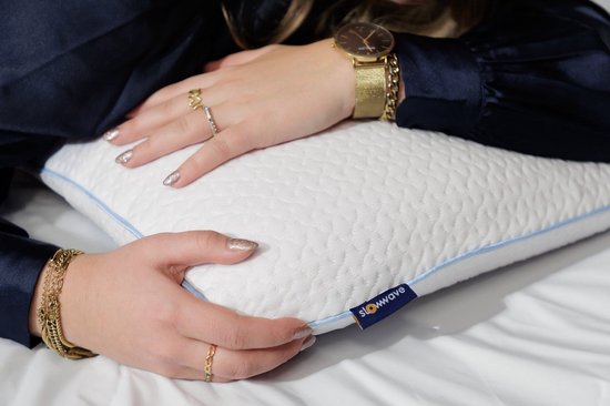 Gedetailleerd schot van een vrouw die op een wit kussen met blauwe bies ligt, met een gouden horloge en ringen.