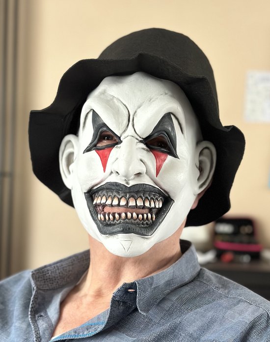 Eng masker met witte gezicht, rode tranen onder de ogen, zwarte oogmake-up, grote grijns, zwarte hoed.