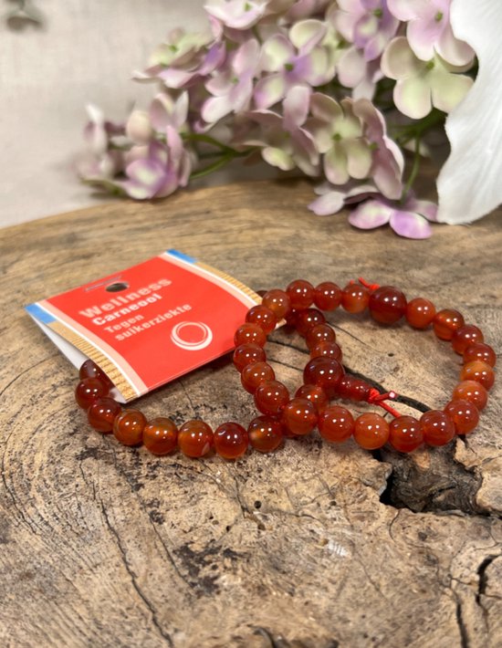 Twee oranje carneool armbanden met rode draden en label op hout