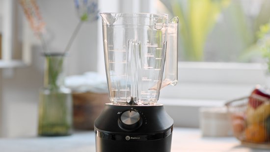 Glazen blenderkan met maatstrepen en handvat, geplaatst op een zwarte blenderbasis met draaiknop.