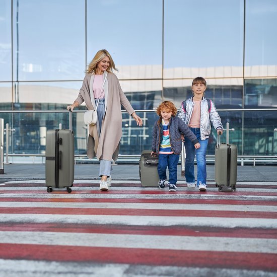 Vrouw en twee kinderen met bagage op een zebrapad.