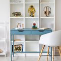 Een blauw bureau met een transparante stolp met bloemen en een model van een tram café op een plank.