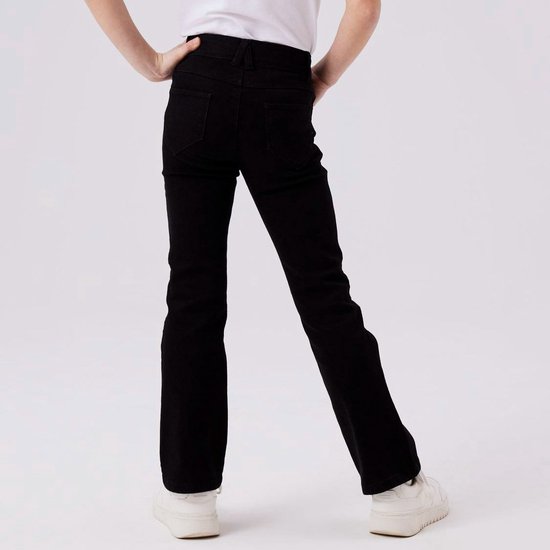 Meisje met de rug naar de camera, draagt een zwarte flared jeans en witte sneakers.