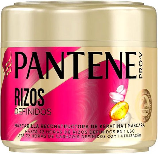 Pot doré avec logo PANTENE PRO-V, accents roses et dorés. Mentionne "RIZOS DEFINIDOS" et "MASCARILLA RECONSTRUCTORA DE KERATINA | MASCARA".