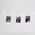 Drie Instax-prints hangend aan een slinger met sterverlichting.