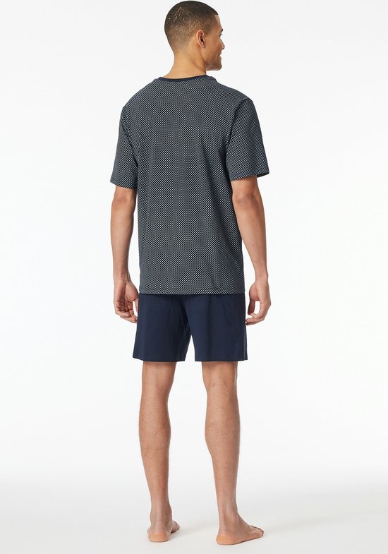 Man van achteren gezien, draagt een donkerblauwe pyjamaset met een ruitjespatroon op het shirt.